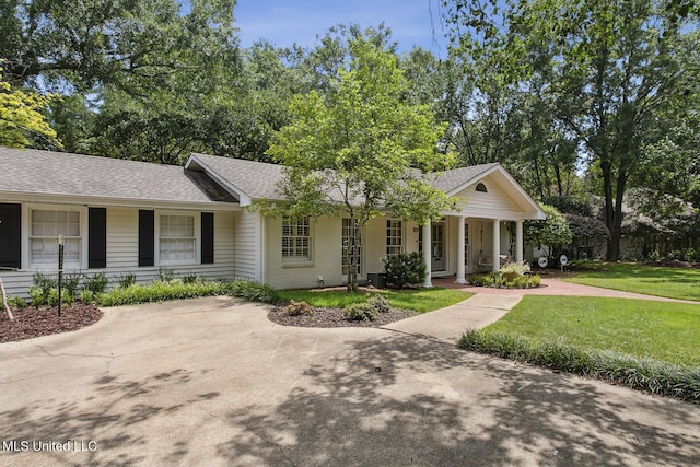 ranch-style house with a front yard, a porch, and roof with shingles