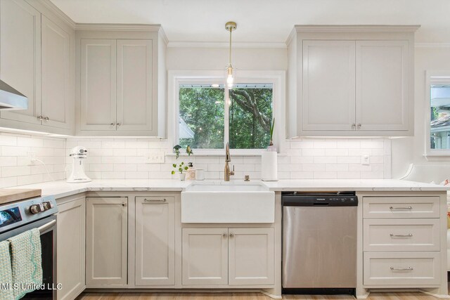 kitchen featuring appliances with stainless steel finishes, sink, backsplash, pendant lighting, and ornamental molding