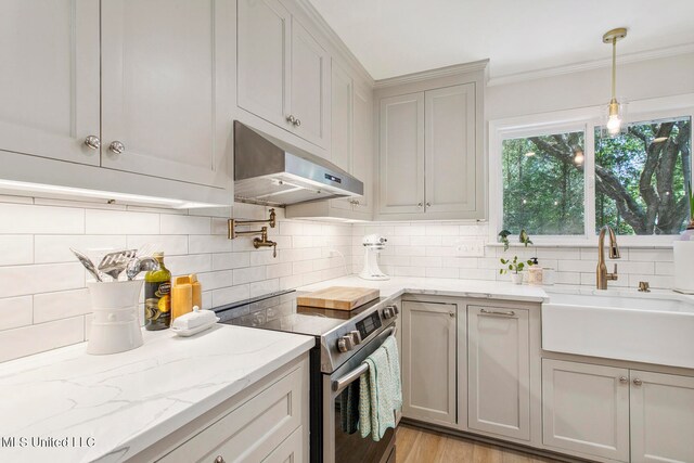 kitchen with sink, backsplash, light hardwood / wood-style floors, pendant lighting, and stainless steel range