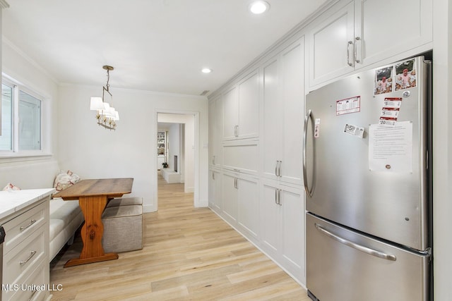 kitchen with freestanding refrigerator, light wood-style floors, white cabinets, and ornamental molding
