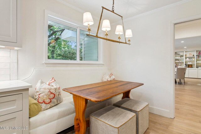 dining area with an inviting chandelier, ornamental molding, and light wood-type flooring