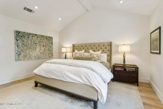 bedroom with lofted ceiling with beams and light hardwood / wood-style flooring