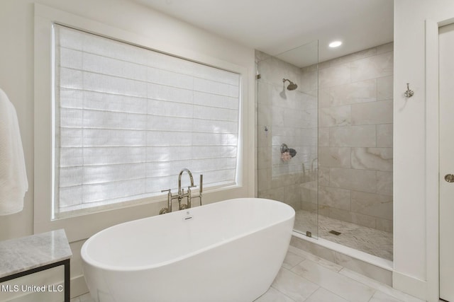 bathroom with a freestanding bath, marble finish floor, and a tile shower