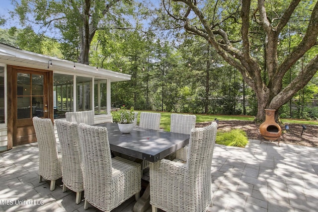 view of patio featuring outdoor dining area and a sunroom