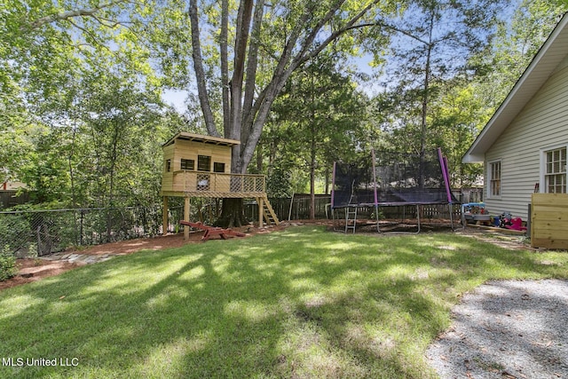 view of yard with a fenced backyard, a deck, and a trampoline