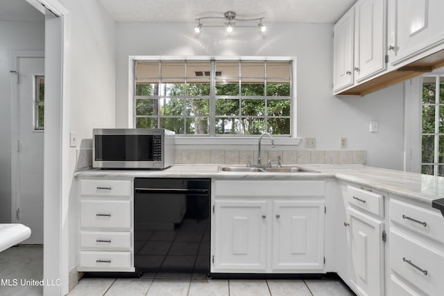 kitchen featuring light tile patterned flooring, white cabinetry, stainless steel microwave, a sink, and dishwasher