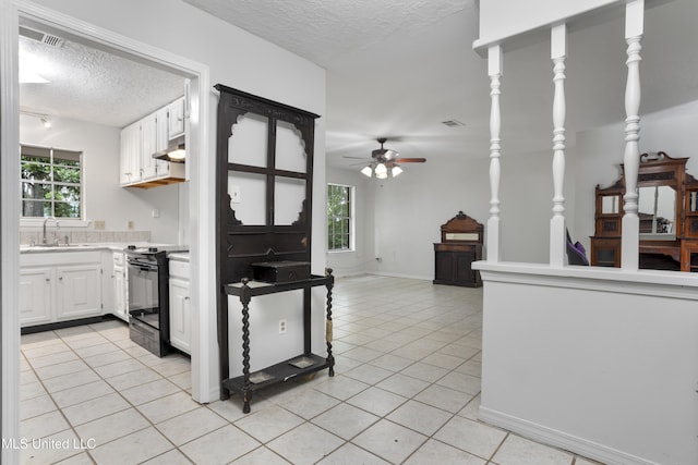 kitchen featuring ceiling fan, a textured ceiling, black electric range oven, a sink, and light tile patterned flooring