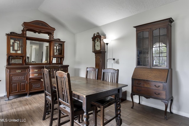 dining area featuring baseboards, vaulted ceiling, and wood finished floors