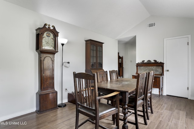 dining space featuring baseboards, lofted ceiling, light wood-style flooring, and visible vents