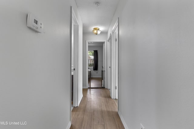 hallway featuring baseboards and light wood-type flooring