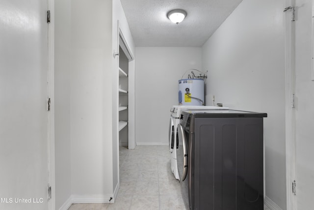 laundry area with laundry area, a textured ceiling, baseboards, water heater, and separate washer and dryer