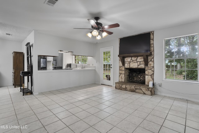 unfurnished living room featuring light tile patterned flooring, ceiling fan, a sink, a fireplace, and visible vents