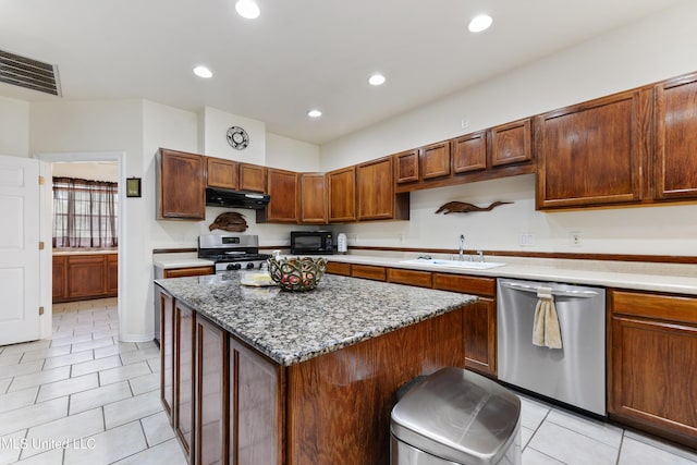 kitchen with sink, light tile patterned floors, appliances with stainless steel finishes, light stone countertops, and a kitchen island