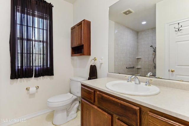 bathroom with vanity, a tile shower, and toilet