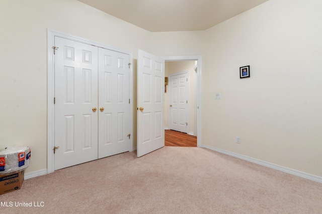 unfurnished bedroom featuring light colored carpet and a closet