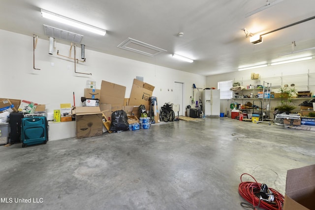 garage featuring a workshop area and white fridge with ice dispenser