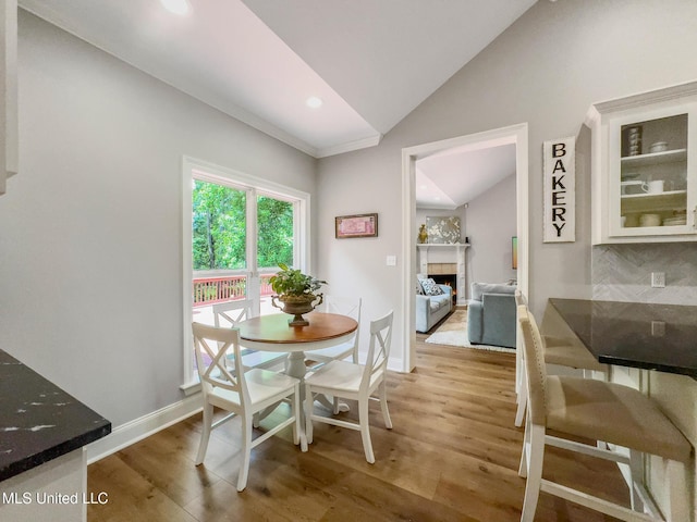 66 Auburn Pl, Hattiesburg, MS 39402 - dining area with lofted ceiling, light wood-type flooring, a warm lit fireplace, baseboards, and recessed lighting