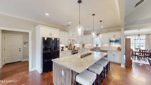 kitchen featuring white cabinets, pendant lighting, appliances with stainless steel finishes, and a center island