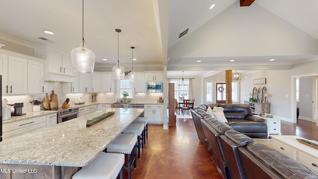 kitchen with white cabinetry, a breakfast bar area, appliances with stainless steel finishes, a spacious island, and pendant lighting