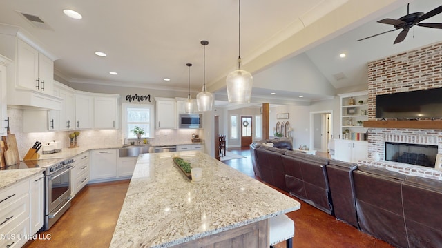 kitchen featuring white cabinetry, appliances with stainless steel finishes, light stone countertops, pendant lighting, and a center island