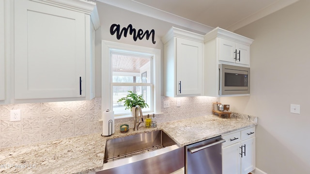 kitchen with white cabinetry, stainless steel appliances, backsplash, light stone countertops, and sink