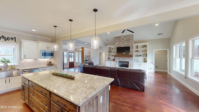 kitchen featuring a center island, sink, white cabinetry, hanging light fixtures, and appliances with stainless steel finishes