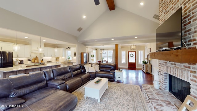 living room featuring an inviting chandelier, high vaulted ceiling, light wood-type flooring, a brick fireplace, and beam ceiling