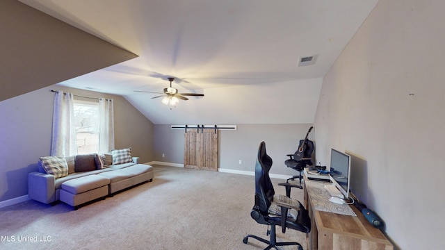 carpeted office with ceiling fan, a barn door, and vaulted ceiling