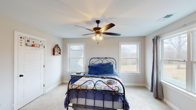 bedroom featuring ceiling fan, light colored carpet, and multiple windows