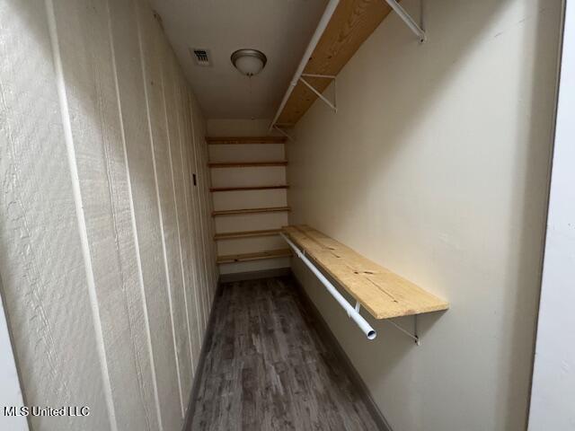 walk in closet with attic access, dark wood finished floors, and visible vents