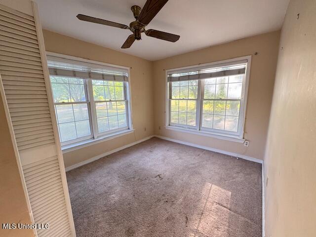 carpeted empty room with baseboards and a ceiling fan