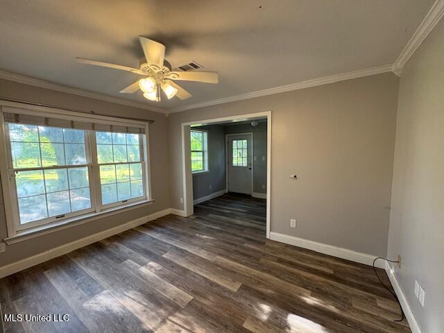 unfurnished room with visible vents, dark wood finished floors, crown molding, a ceiling fan, and baseboards