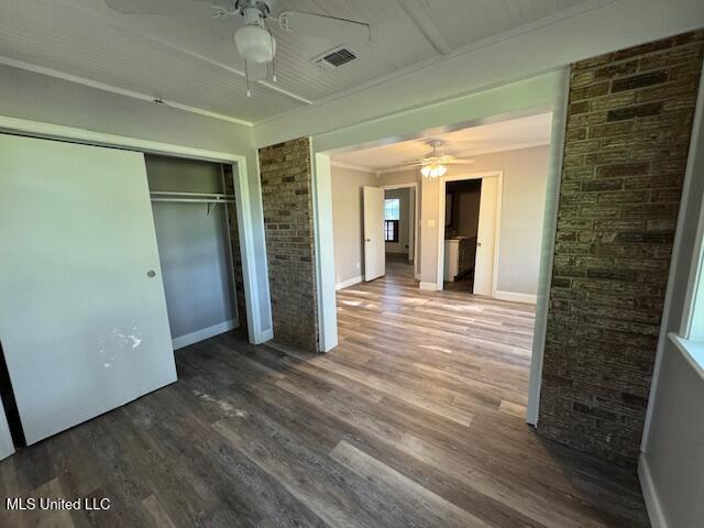 unfurnished bedroom with a closet, wood finished floors, visible vents, a ceiling fan, and baseboards