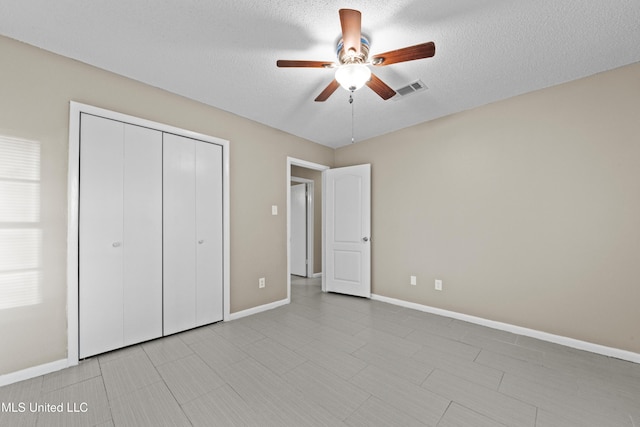 unfurnished bedroom with a textured ceiling, ceiling fan, and a closet