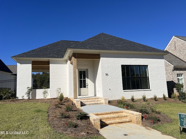 view of front facade featuring a front lawn and a shingled roof