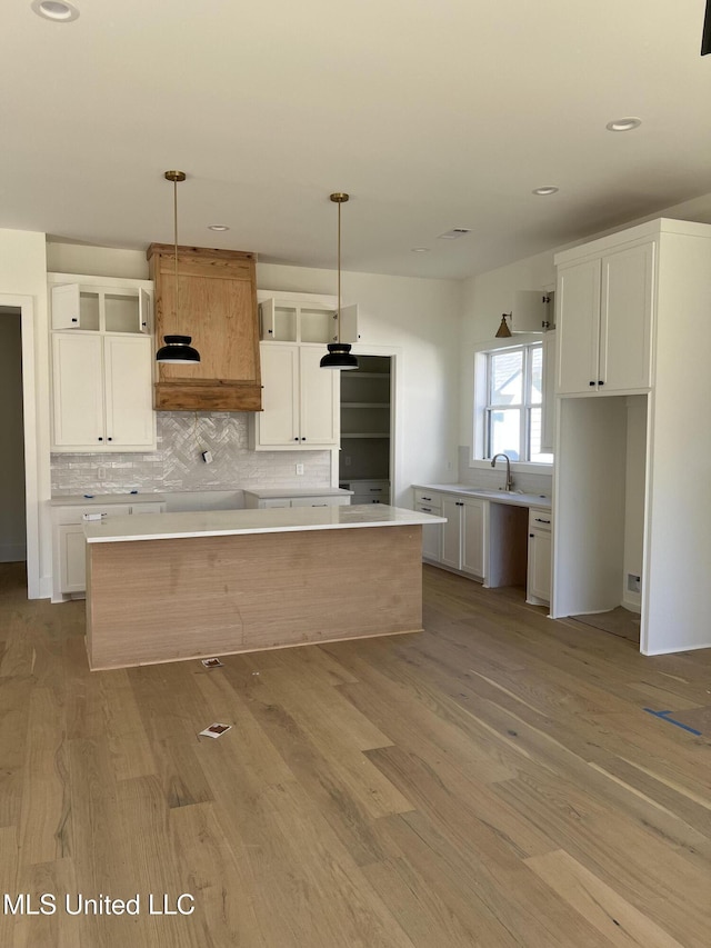 kitchen featuring white cabinets, wood finished floors, backsplash, and a center island