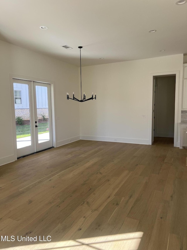 unfurnished dining area featuring wood finished floors, visible vents, french doors, and baseboards