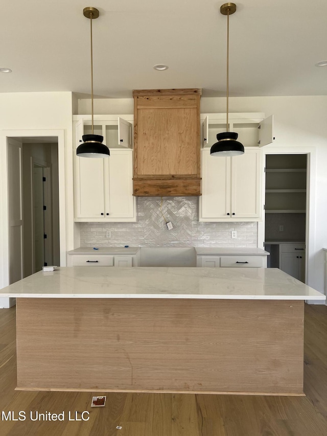 kitchen with tasteful backsplash, hanging light fixtures, white cabinetry, and dark wood-type flooring