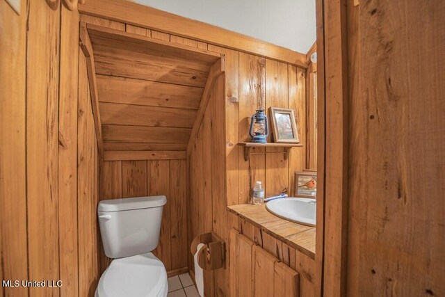 bathroom featuring tile patterned floors, vanity, toilet, and wood walls