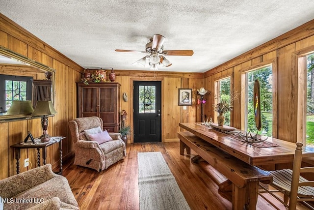 interior space featuring hardwood / wood-style flooring, ceiling fan, and wood walls