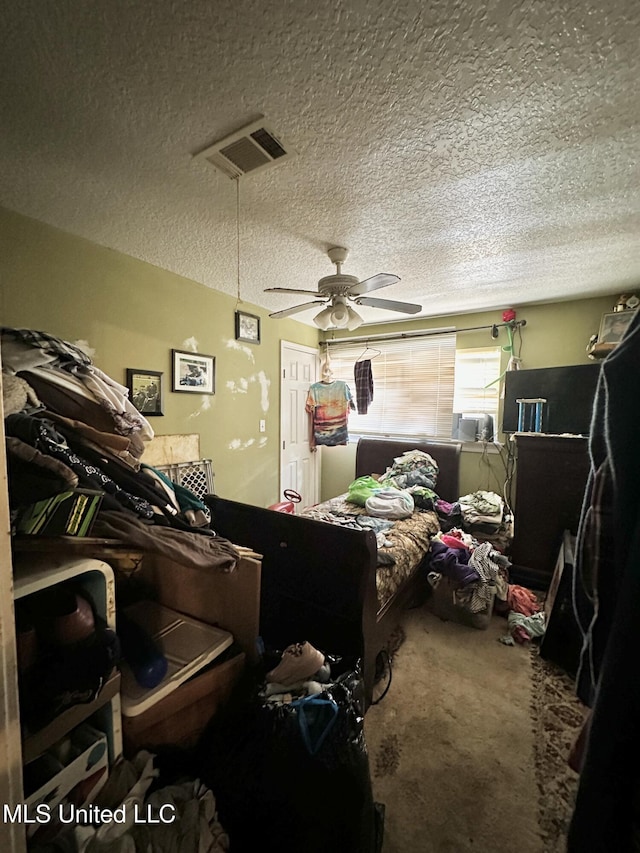 bedroom with a textured ceiling, carpet, and a ceiling fan