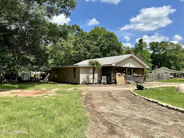 view of front of house with dirt driveway, covered porch, and view of scattered trees