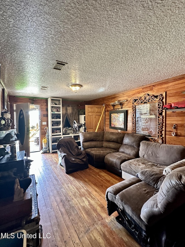 living room with wood walls, a textured ceiling, and hardwood / wood-style floors