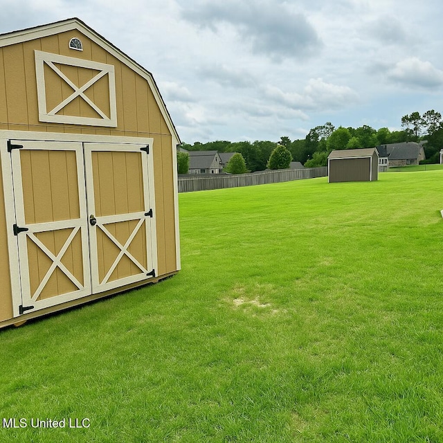 view of yard featuring fence, a storage unit, and an outdoor structure