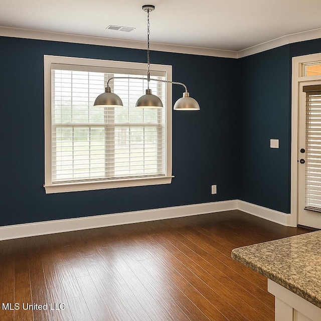 unfurnished dining area with baseboards, visible vents, ornamental molding, and dark wood finished floors