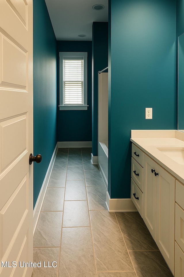 full bath with baseboards,  shower combination, tile patterned flooring, and vanity