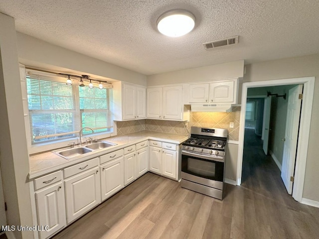 5448 Crepe Myrtle Dr, Jackson, MS 39206 - kitchen with stainless steel range with gas stovetop, a sink, under cabinet range hood, light countertops, and a textured ceiling
