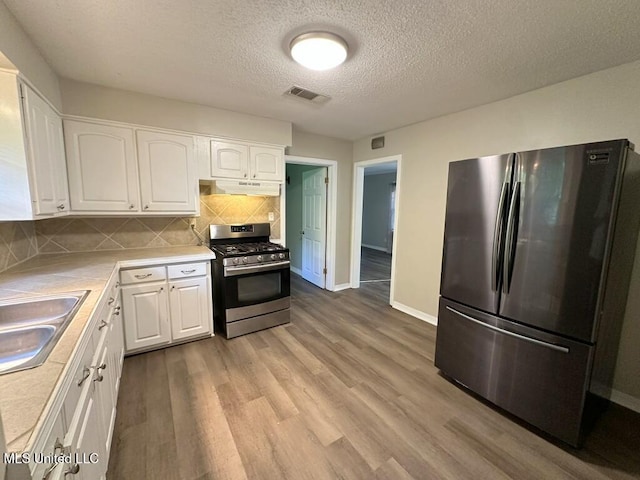 5448 Crepe Myrtle Dr, Jackson, MS 39206 - kitchen featuring stainless steel appliances, under cabinet range hood, white cabinets, light countertops, and backsplash