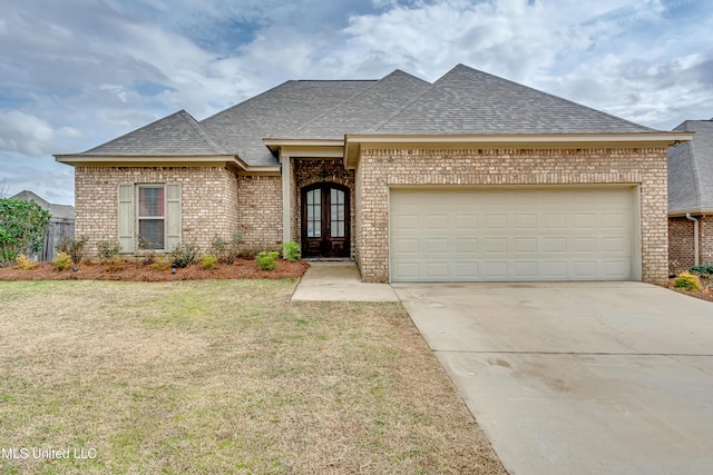 view of front facade featuring a garage, a front yard, and french doors