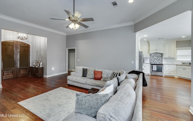 living room featuring sink, wood-type flooring, ornamental molding, and ceiling fan